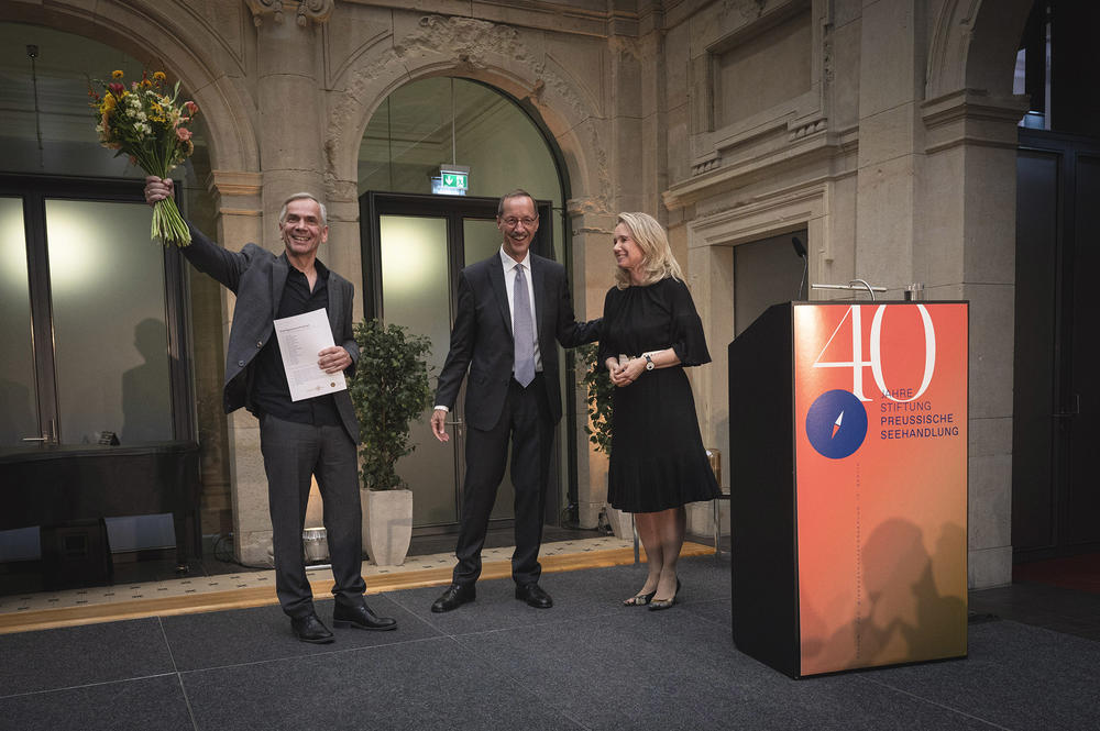 Lutz Seiler nimmt Blumen und Urkunde entgegen, rechts: Dr. Hans Gerhard Hannesen und Sarah Wedl-Wilson