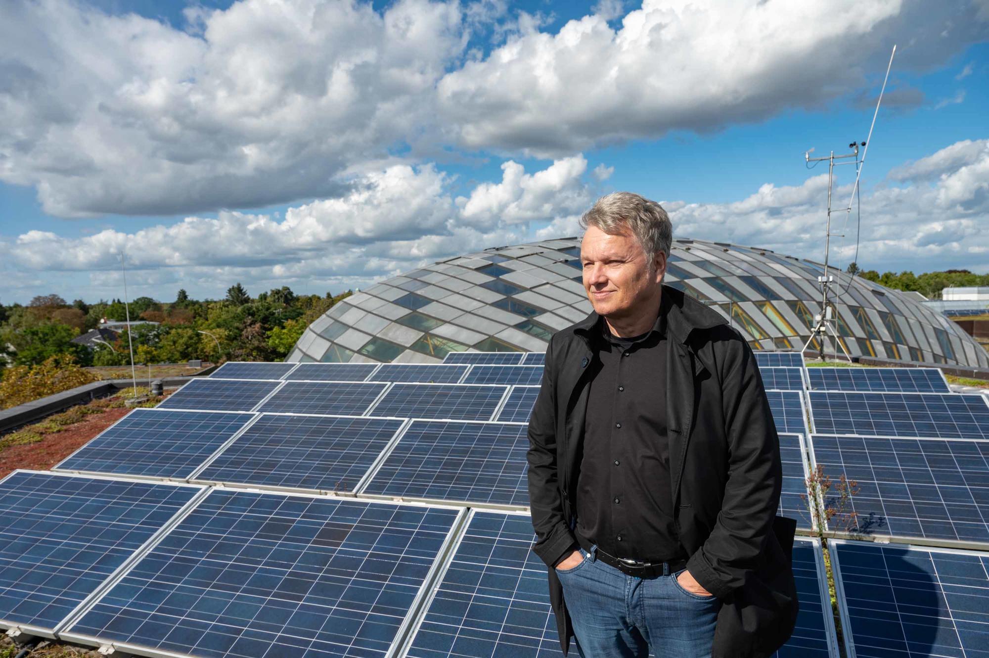 Andreas Wanke auf dem Dach der Rost- und Silberlaube, das mit Solarzellen bestückt ist, im Hintergrund die Kuppel der Philologischen Bibliothek.